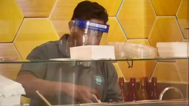 A shop worker behind protective equipment