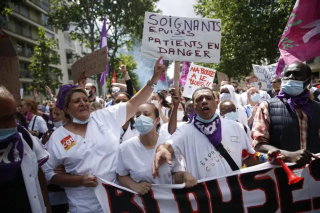 Hospital workers hold signs reading "medical staff exhausted, patients in danger" as they march during a protest in June