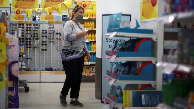 A woman wearing a protective face mask is seen in a shop