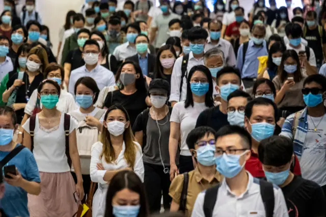 Passengers wearing protective masks walk through the Hong Kong Station