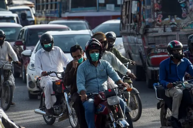 Motorcyclists in the city of Karachi wear masks