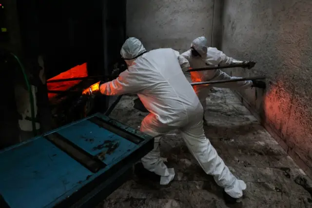 Crematorium workers enter the body of a person who died of Covid-19 in Mexico City, Mexico. Photo: 15 July 2020