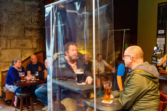 Drinkers behind a plastic screen at Glasgow's Ben Nevis pub