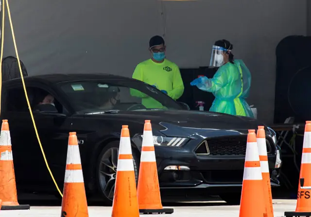 Health care workers direct a driver to be tested for Covid-19 in Miami Gardens, Florida