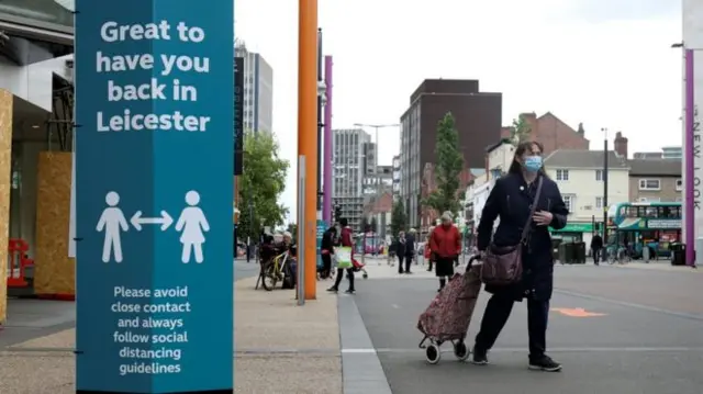 A woman in a mask walking through Leicester