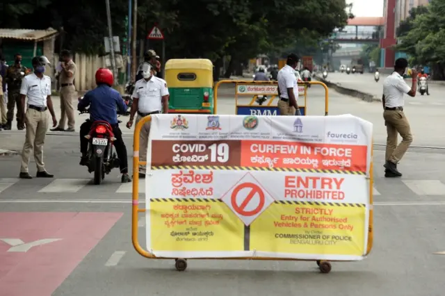 Indian policemen stop people riding scooters in Bangalore