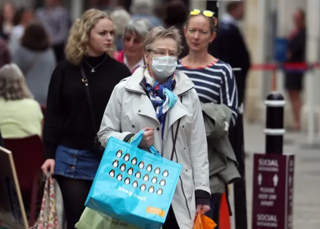 A woman out shopping on the high street with a face mask on