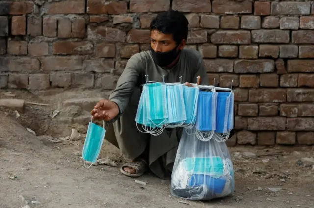 A man sells protective masks outside a cattle market in Peshawar