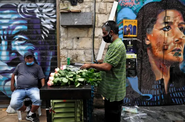 A vendor at a market stall in Jerusalem wears a mask