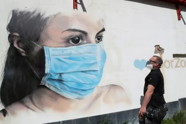 An artist finishes a mural of a woman wearing a mask in Antwep