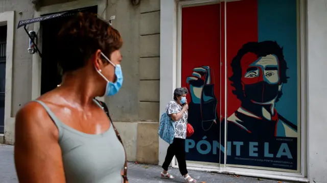 Graffiti in Barcelona depicting the director of Spain's Center for Coordination of Health Alerts and Emergencies, Fernando Simon, holding a face mask reads "put it on".