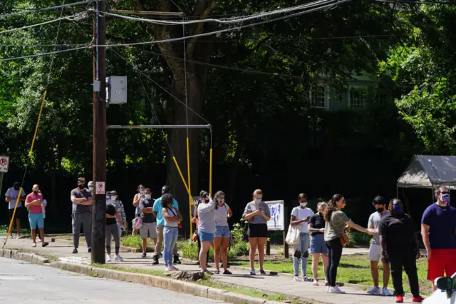 People stand in line to get tested for Covid-19 at a free walk-up testing site in Atlanta, Georgia (11 July)