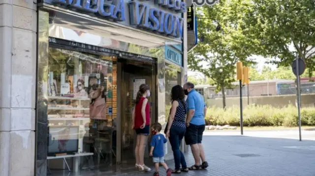 A family waits to enter an optician while one of the measures to prevent the spread of the coronavirus is to limit the capacity of stores,