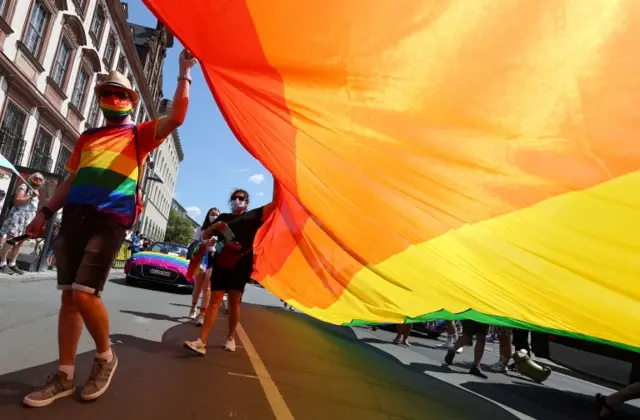 Revellers walk along a Frankfurt street carrying a pride flag