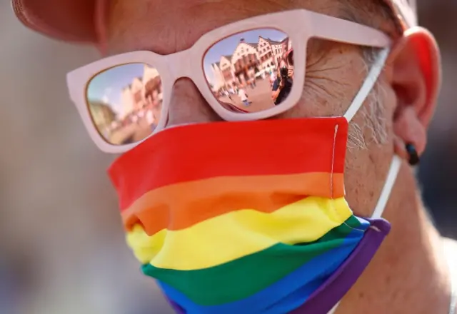 A person wears a rainbow coloured mask at a parade in Frankfurt