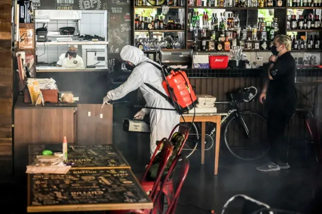 A man disinfects a restaurant in Envigado municipality, near Medellin, Colombia, on July 1, 2020, amid the Covid-19 pandemic