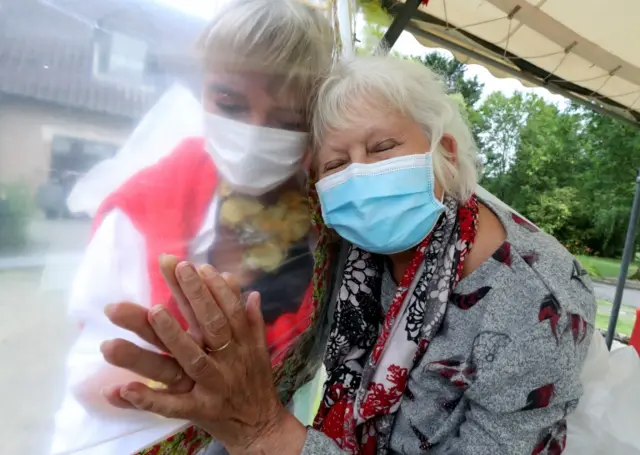 Nursing home residents hug through a plastic screen in Belgium