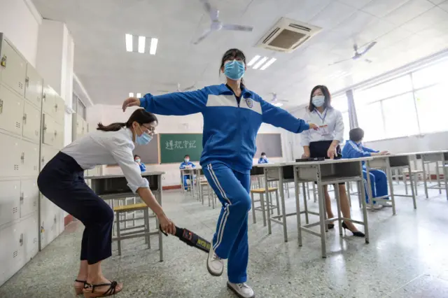 A student undergoes a security check before a simulation of the annual national college entrance exam, also known as Gao Kao, in Handan in China's central Hebei province