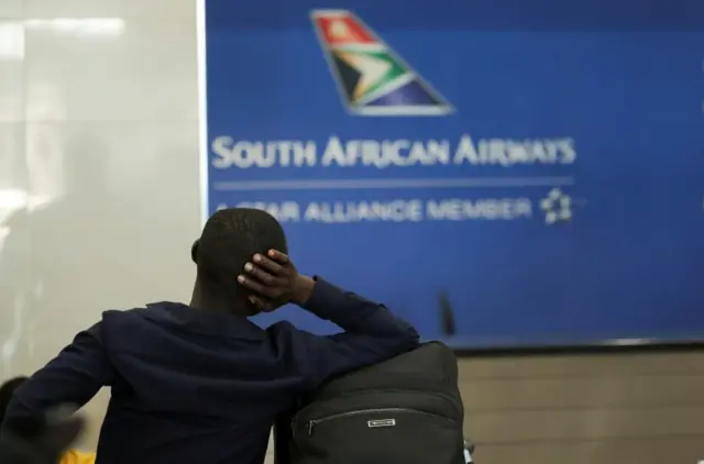 A passenger is seen at the South African Airways customer desk after SAA announced an immediate suspension of all intercontinental flights in response to a travel ban in March