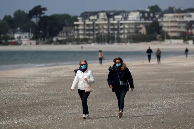 People, wearing protective face masks, walk on the beach of La Baule as France softens its strict lockdown rules during the outbreak of the coronavirus disease (COVID-19) in France, 13 May 2020.