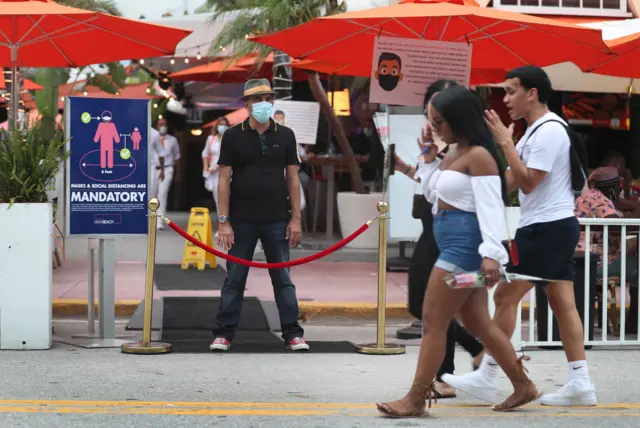 Staff member blocks off entrance as curfew starts in Miami