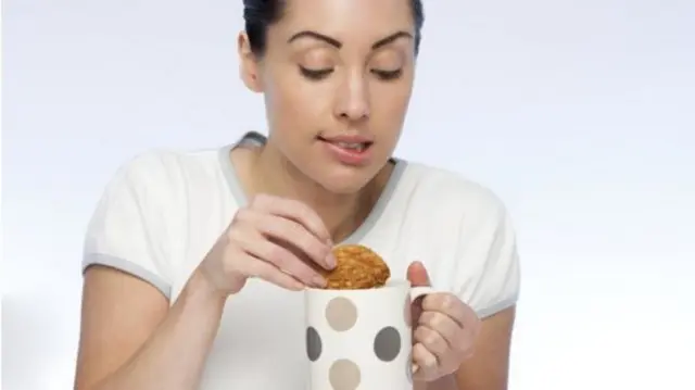 Woman dunking a biscuit in tea