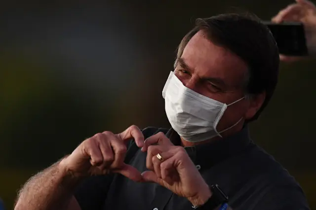 Jair Bolsonaro makes a heart shape with his hands to supporters from the Alvorada Palace in Brasilia