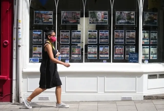 Woman walks past an estate agent window