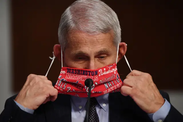 Dr Fauci removes a Washington Nationals protective mask during a Senate hearing in Washington DC