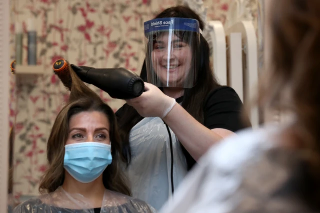 Salon manager Gemma Inglis works on the hair of Shireen Inglis at The Lunatic Fringe in Glasgow as they demonstrate some of the changes put in place to help protect against coronavirus.