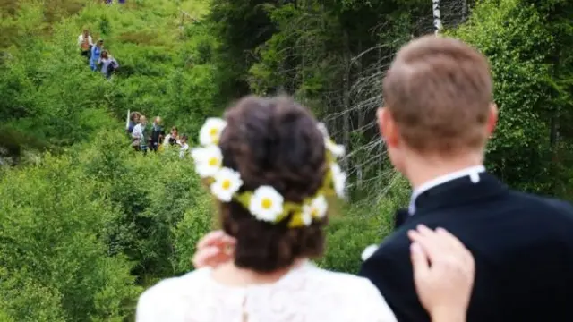 A bride watches as wedding guests arrive for a wedding across a border