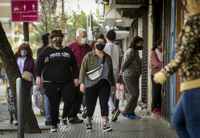 People wearing a protective masks walk around a commercial area in Cuenca street in Buenos Aires,