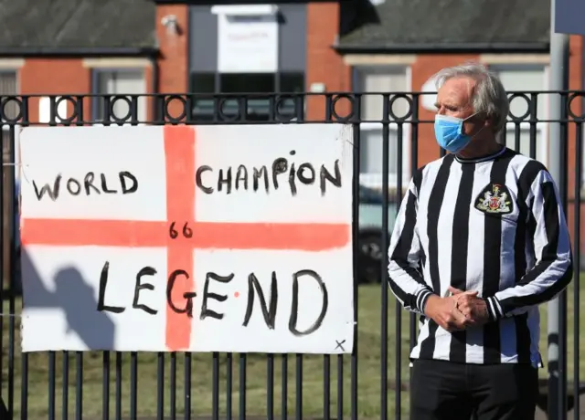 Man in Newcastle shirt next to sign