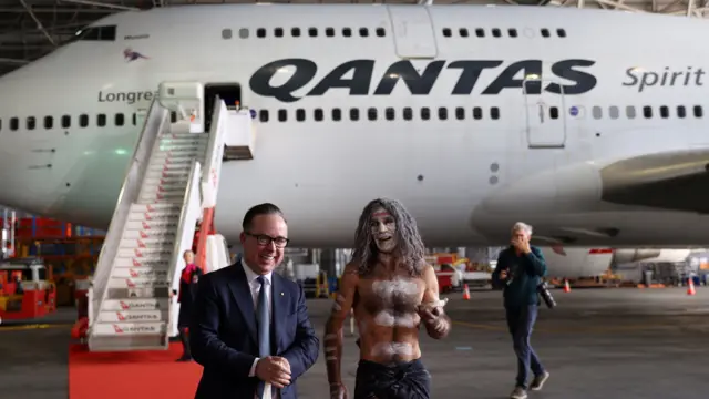 Alan Joyce and an indigenous Australian walk in front of a Qantas 747 jumbo jet