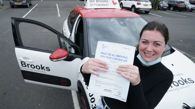 Jade Paxton, 30, a keyworker from Bedlington, Northumberland, holds up her pass certificate after successfully completing her driving test in Blyth, Northumberland.