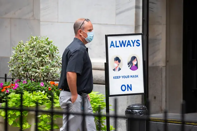 A person passes a sign that reads "Always Keep Your Mask On" outside the New York Stock Exchange