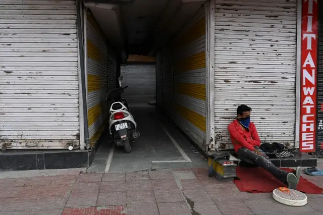 A man sits outside closed shops in Srinagar, Kashmir