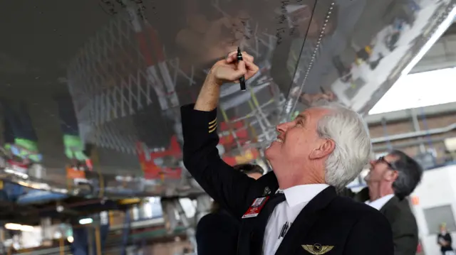 A Qantas pilot writes a message on the bottom of a Qantas 747 jumbo jet