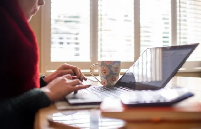 A woman works at her laptop at home