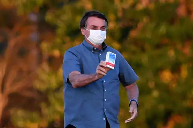 Brazilian President Jair Bolsonaro shows a box of hydroxychloroquine to supporters outside the Alvorada Palace in Brasilia, on July 23, 2020