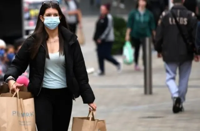 A shopper wears a facemask as she walks in the city centre of Leeds.