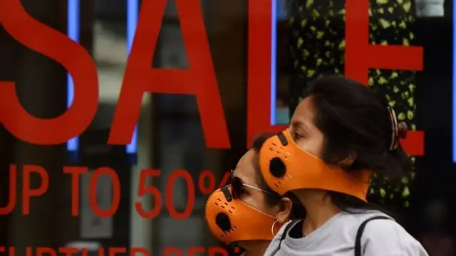 People wearing masks outside a shop