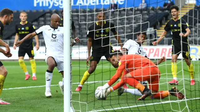 David Raya of Brentford pounces on the ball as Andre Ayew and Rhian Brewster of Swansea City close in