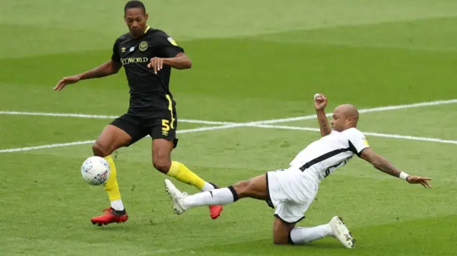 Andre Ayew of Swansea City tackles Ethan Pinnock of Brentford