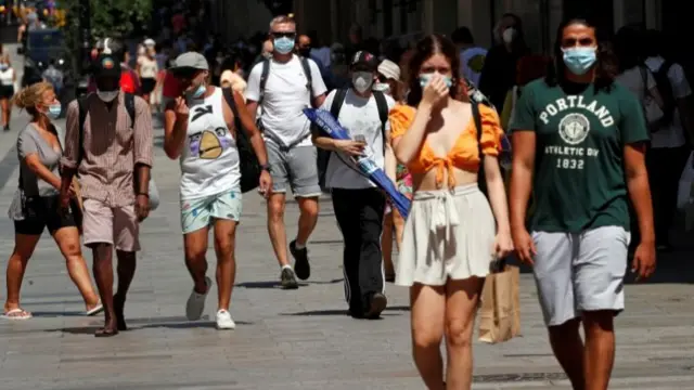 People wear protective face masks as they make their way, amid the coronavirus disease outbreak, in Barcelona, Spain