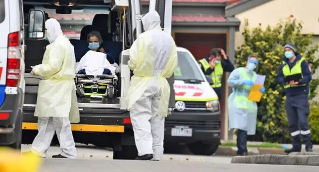 Ambulance officers remove a resident from home in Melbourne