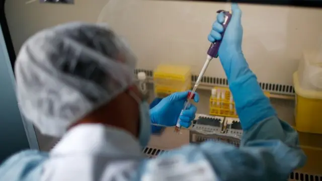 A technician scans test tubes containing live samples