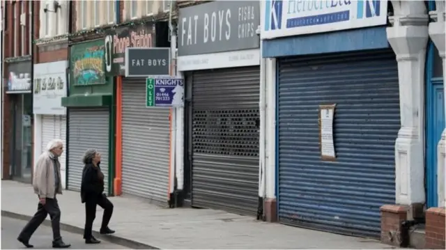 A couple walking past closed shops