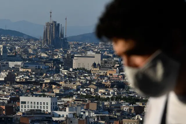 A man wearing a face mask sits at a terrace bar overlooking the Sagrada Familia in Barcelona