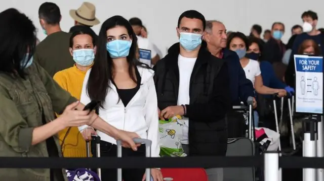 People wear masks as they queue at an airport